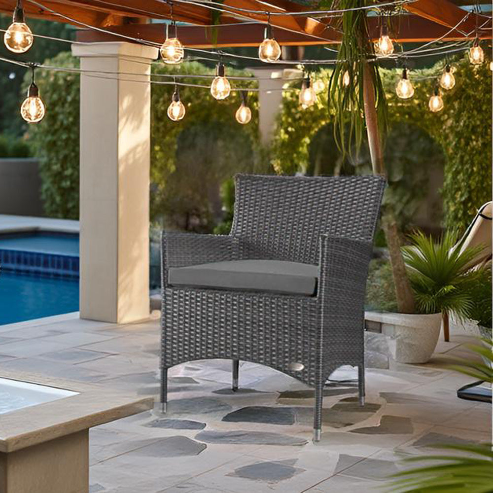 Grauer Rattanstuhl mit grauem Kissen auf Terrasse, umgeben von Lichterkette, Pflanzen und Pool.