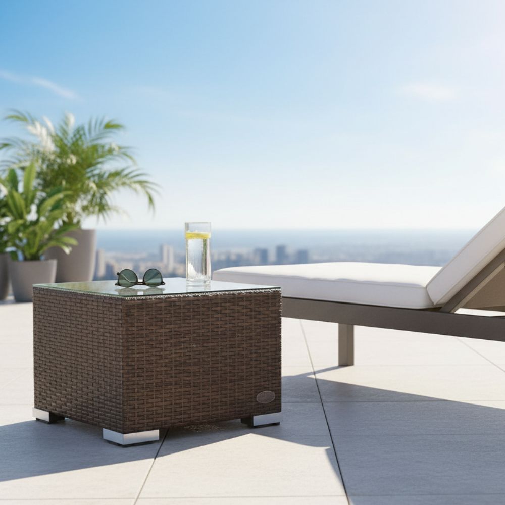 Brauner Polyrattan-Beistelltisch mit Glasplatte neben einer Sonnenliege auf einer Terrasse. Auf der Tischplatte stehen ein Getränk und eine Sonnenbrille.