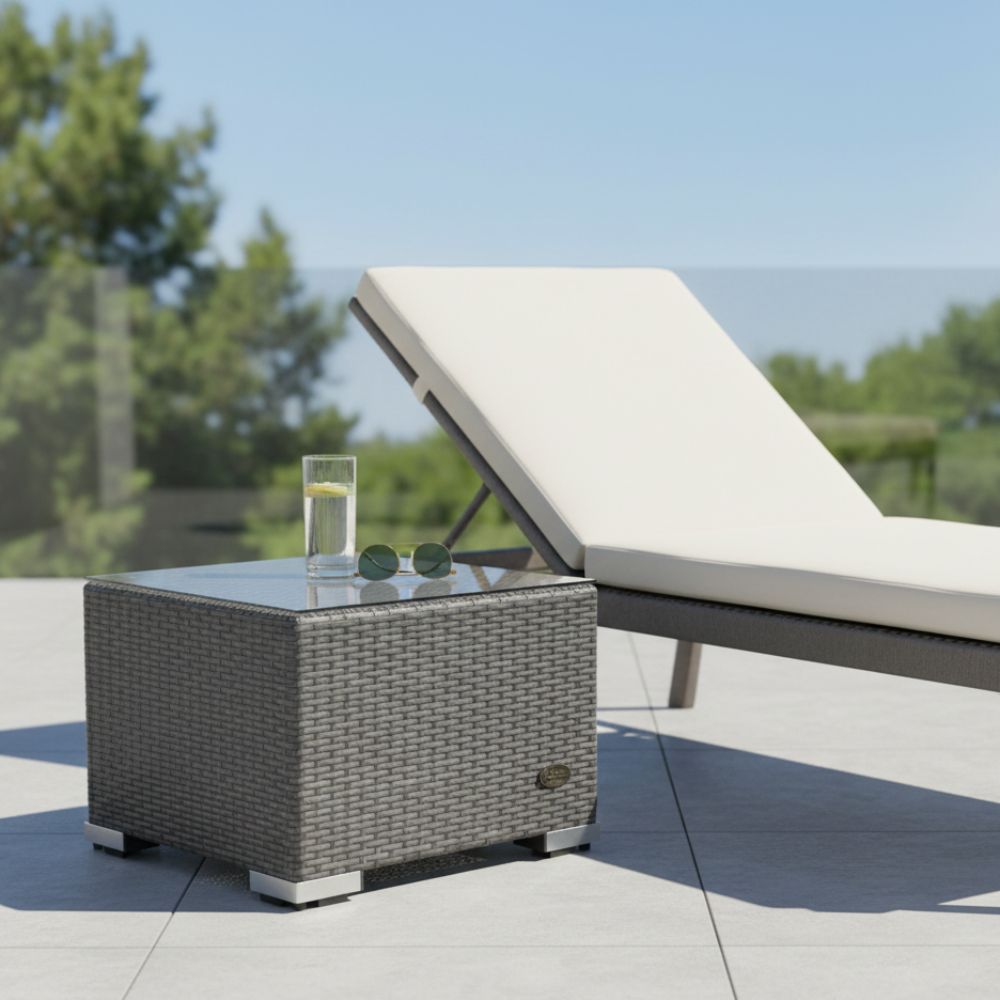Grauer Polyrattan Beistelltisch mit Glasplatte neben einer Sonnenliege auf einer modernen Terrasse