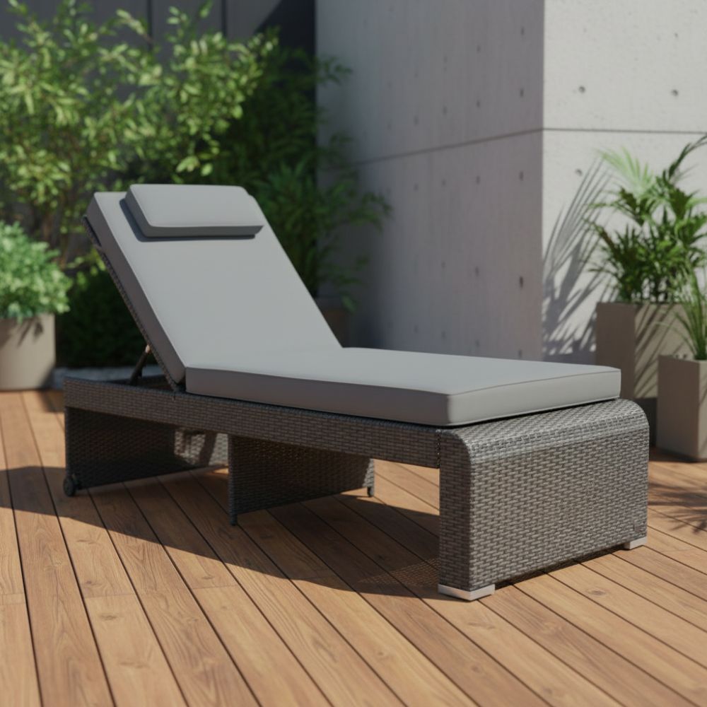 Graue Polyrattan Sonnenliege mit Auflage auf einer Holzterrasse im Garten, moderne Outdoor-Liege zum Entspannen
