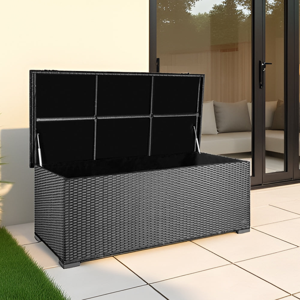 Silber-Graue Garten-Auflagenbox aus Polyrattan mit geöffnetem Deckel auf moderner Terrasse vor Glasfront.