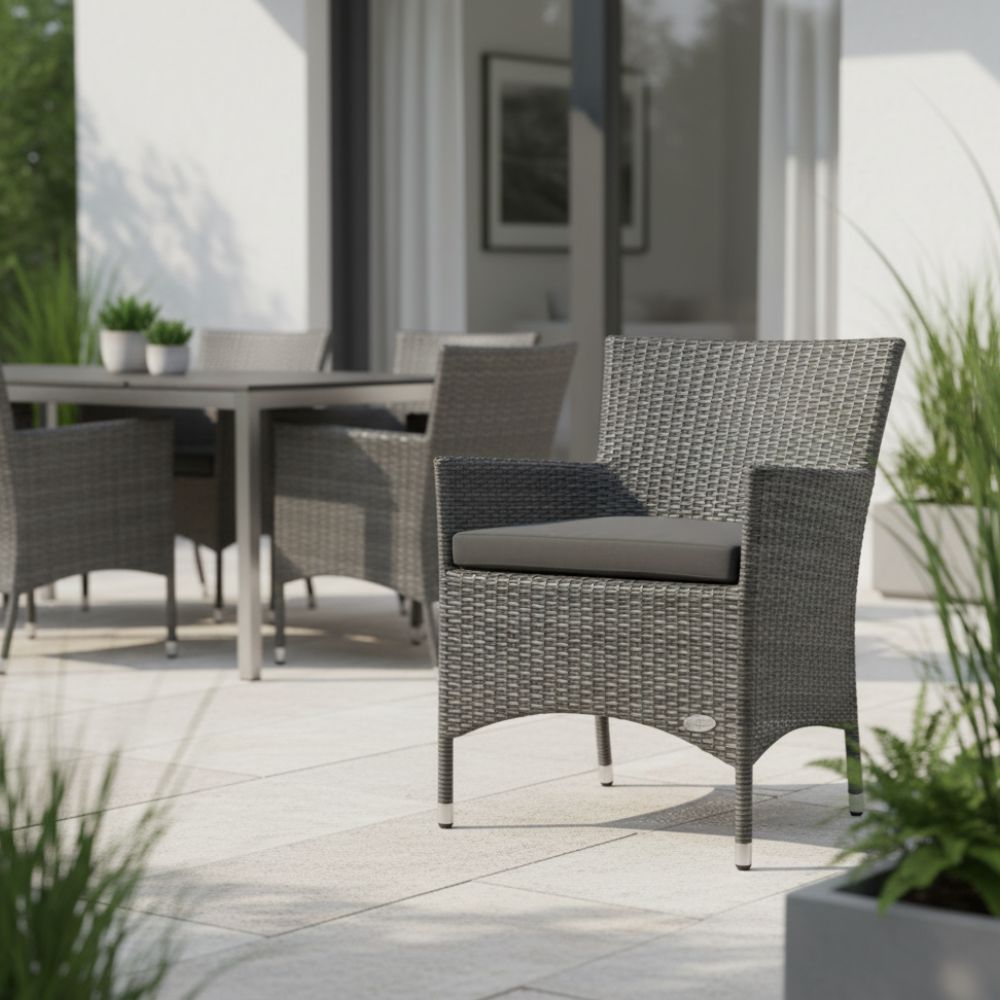 Eleganter Polyrattan-Gartenstuhl „Trento“ in Grau auf heller Terrasse mit Esstisch im Hintergrund. Komfortabler Terrassenstuhl mit ergonomischer Form und wetterbeständigem Sitzkissen.