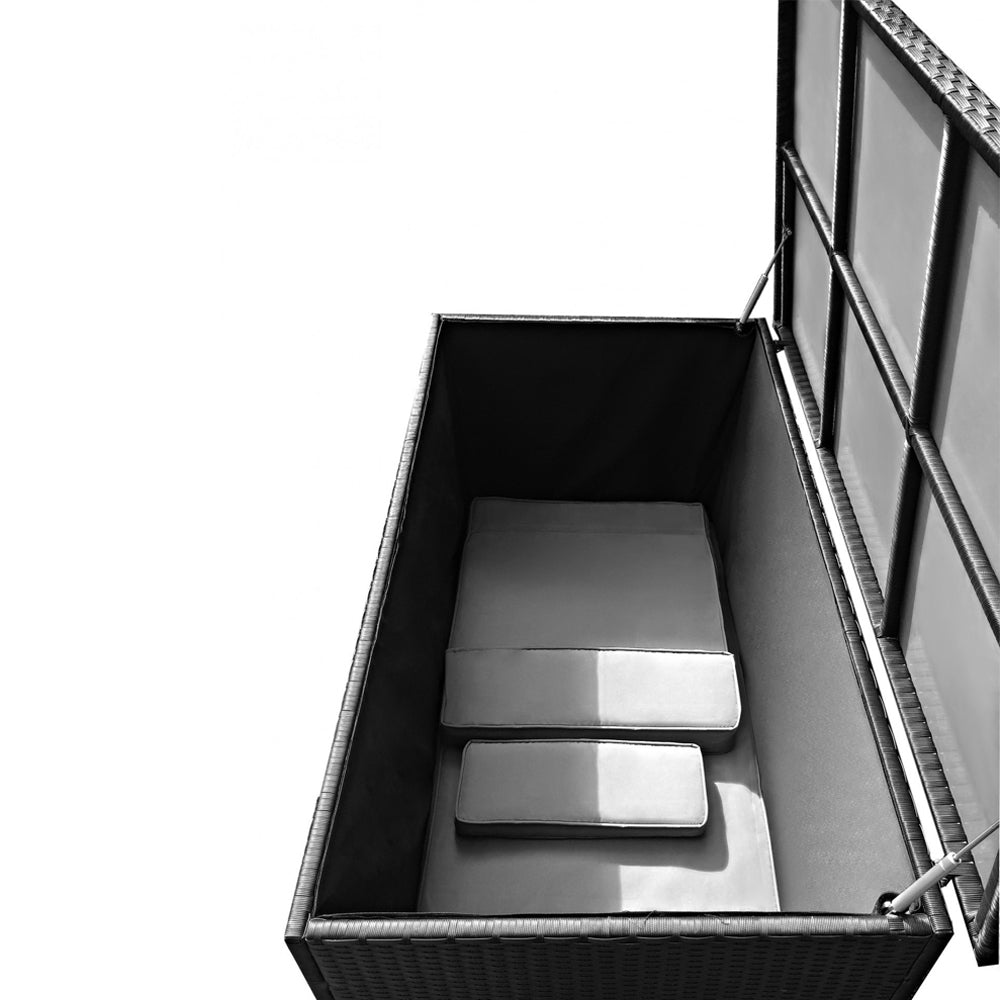 Geöffnete schwarze Aufbewahrungsbox in Rattan-Optik mit innenliegenden Polstern. Der Deckel wird von zwei Gasdruckdämpfern gehalten.