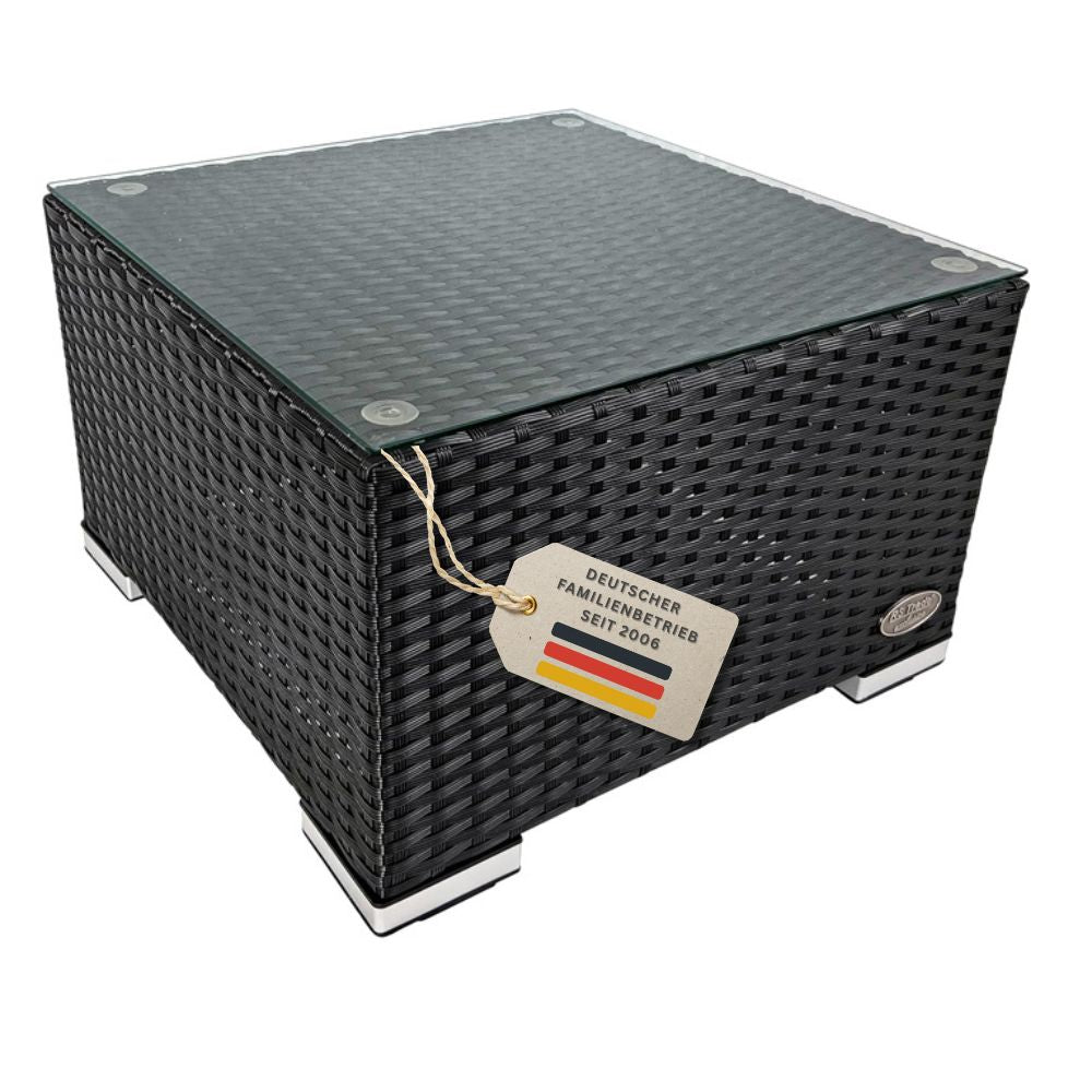 Freigestellter Beistelltisch aus schwarzem Polyrattan mit Glasplatte und Metallfüßen vor weißem Hintergrund.