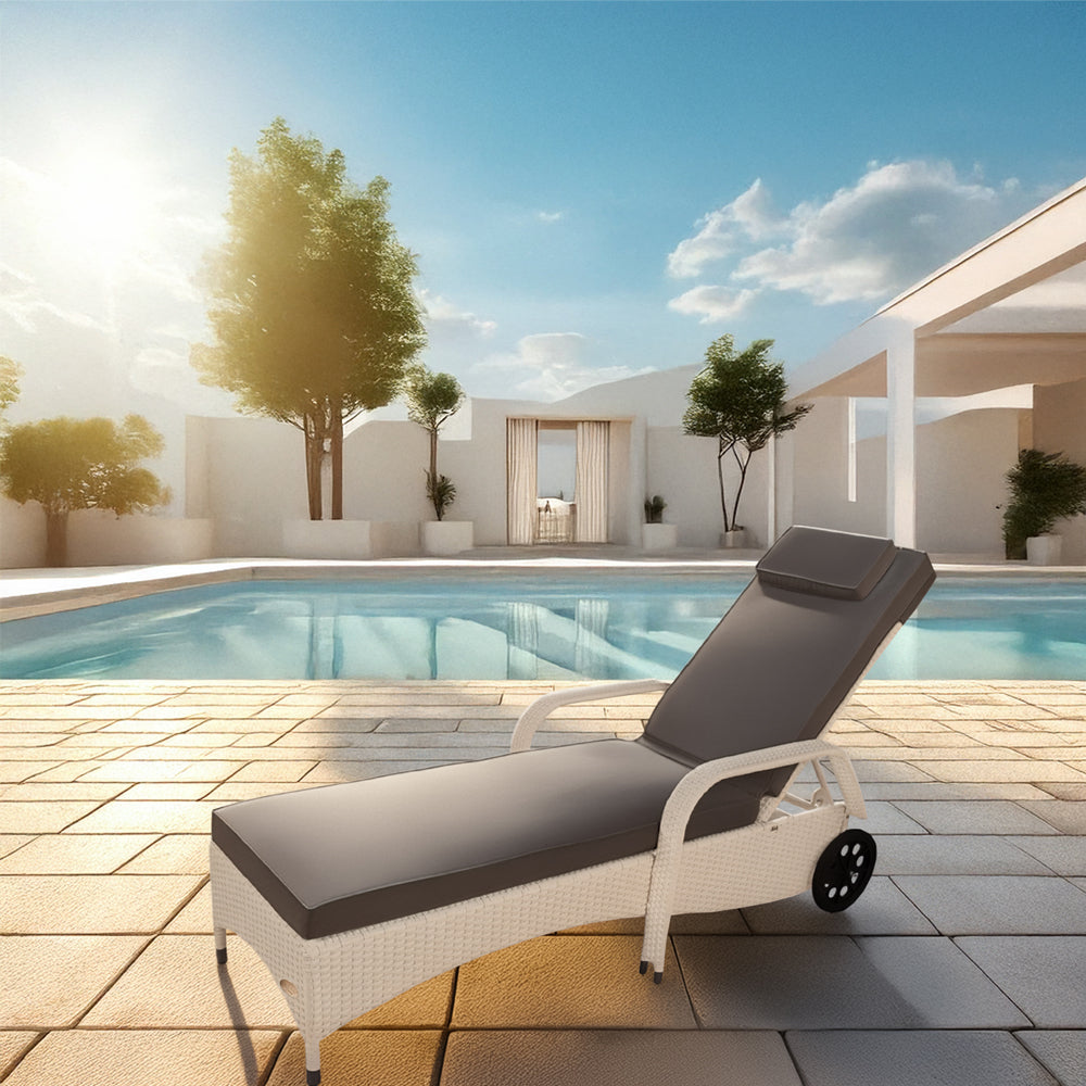 Weißer Rattan-Liegestuhl mit Polster steht in vor einem Pool.