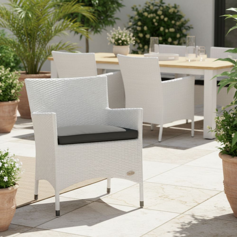 Eleganter Polyrattan-Gartenstuhl „Trento“ in Weiß auf heller Terrasse mit Esstisch im Hintergrund. Komfortabler Terrassenstuhl mit ergonomischer Form und wetterbeständigem Sitzkissen.