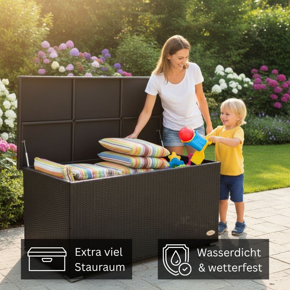 Schwarze Polyrattan Gartenbox mit extra viel Stauraum; Person verstaut Gartenauflagen und Spielzeug in der wetterfesten Aufbewahrungsbox im Garten.