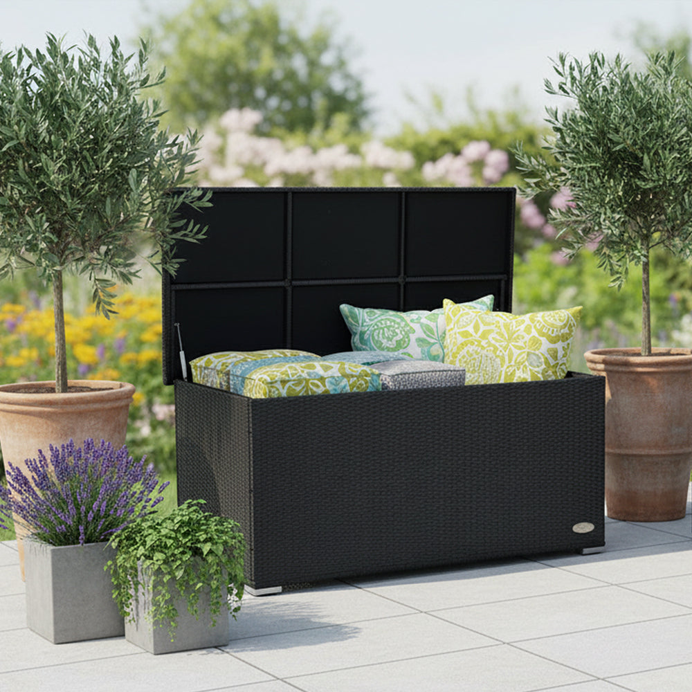 Schwarze Garten-Auflagenbox aus wetterfestem Polyrattan auf der Terrasse mit geöffnetem Deckel und verstauten Sitzkissen im Innenraum.