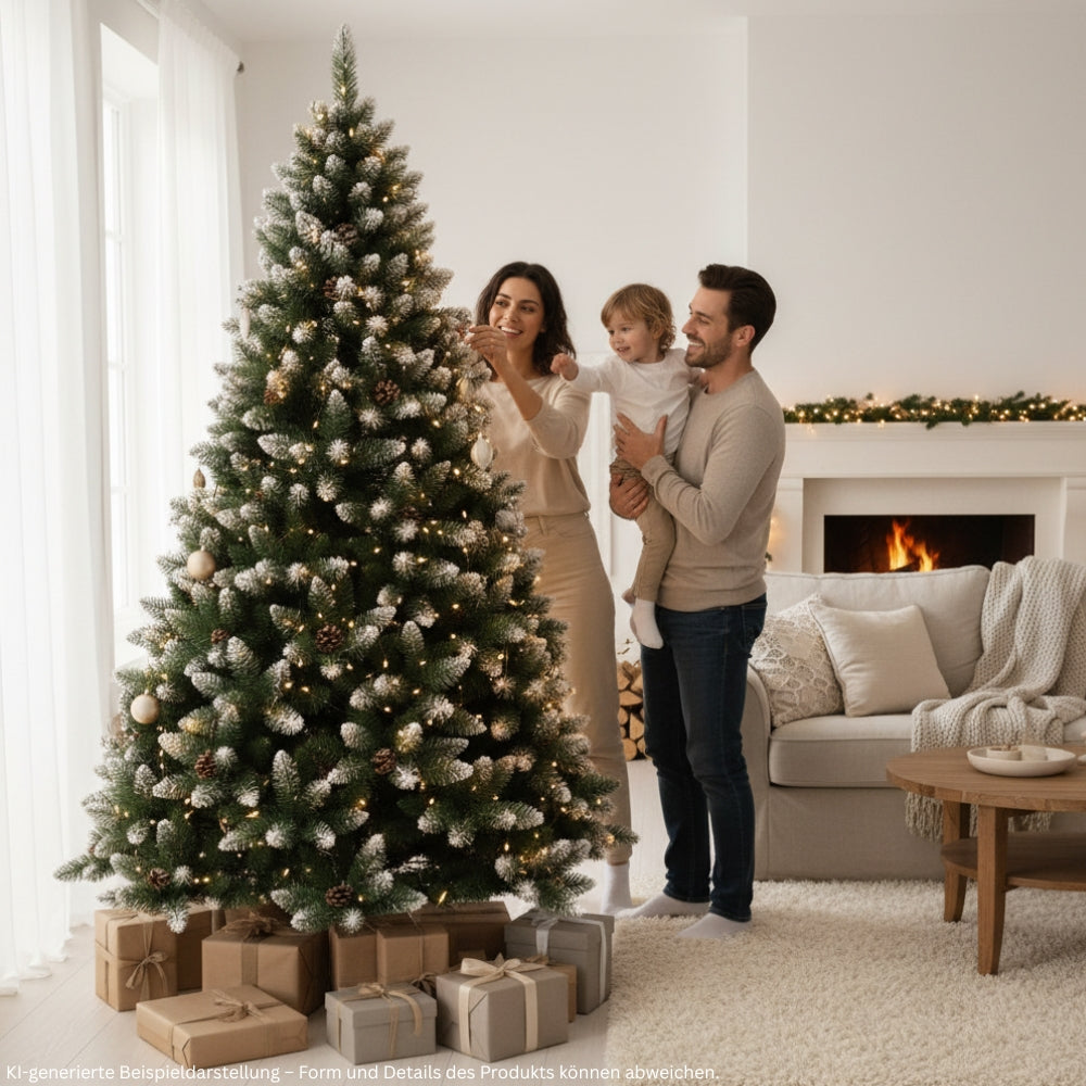Familie schmückt einen künstlichen Weihnachtsbaum mit beschneiten Zweigspitzen, Tannenzapfen und warmweißer Beleuchtung im Wohnzimmer