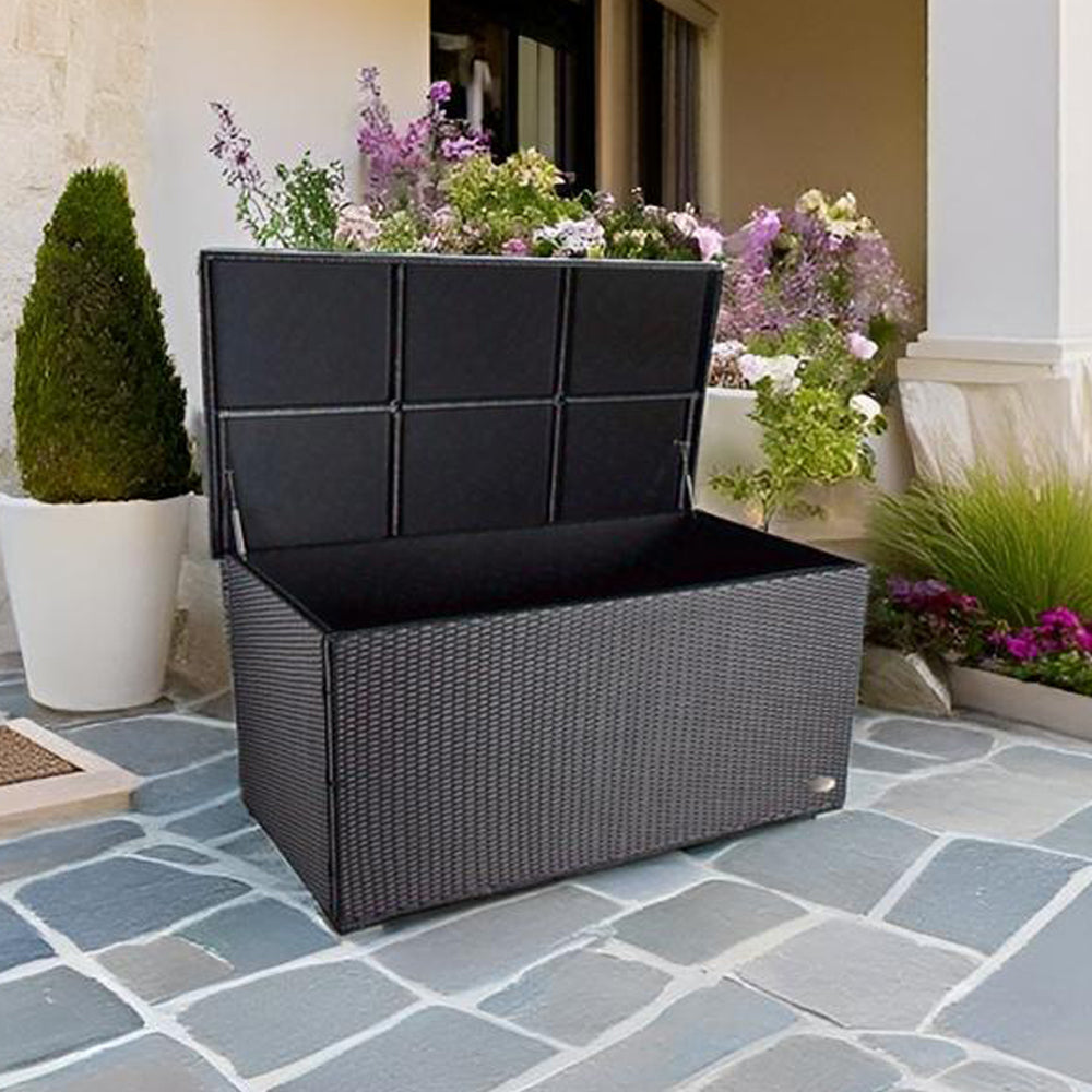 Geöffnete Aufbewahrungsbox in Schwarz auf Stein-Terrasse mit Pflanzen im Hintergrund.