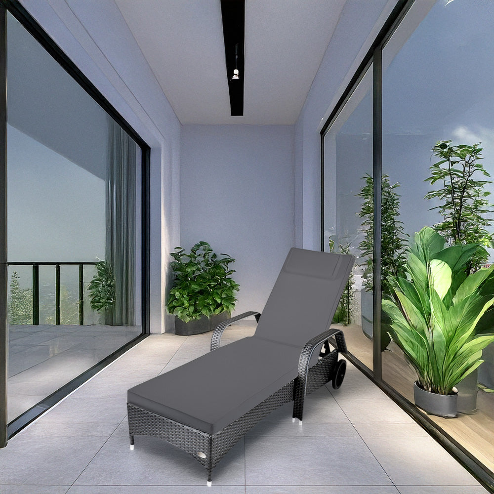 Grauer Liegestuhl in modernem Raum mit Glasfronten, Pflanzen und hellem Fliesenboden.