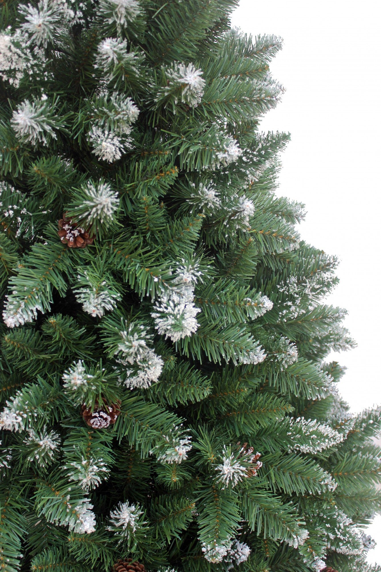 Dicht befüllter künstlicher Weihnachtsbaum mit Schneespitzen und vereinzelt sichtbaren Zapfen. 270 cm
