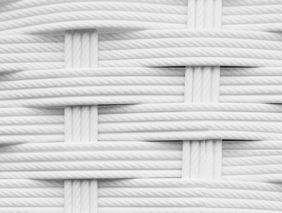 Detailaufnahme eines weißen, handgeflochtenen Polyrattan-Geflechts.